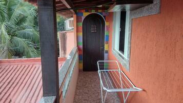 Ein Balkon mit einem Metalltrockner, Fliesenboden und einer farbenfrohen Wand.