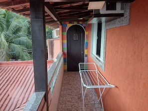 A balcony with a metal drying rack, a tiled floor, and a colorful wall.