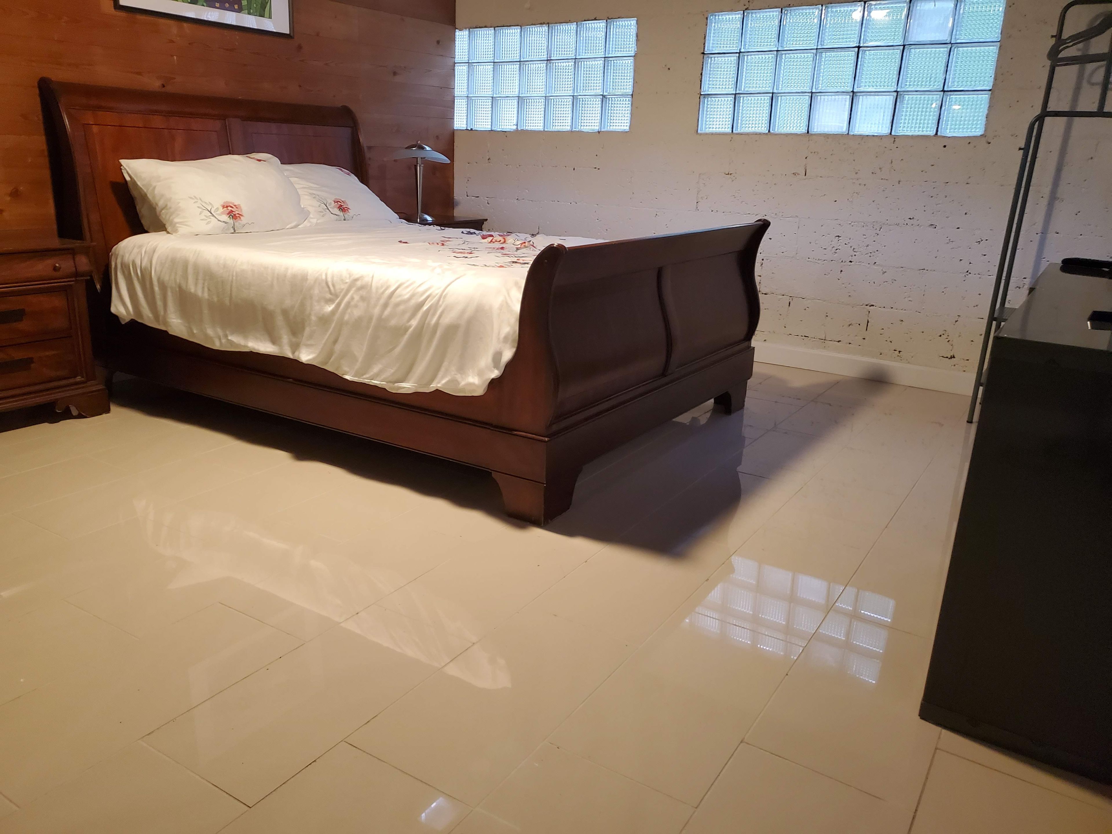 Un dormitorio con una cama de madera, una mesita de noche, una lámpara y una ventana con persianas.