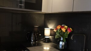 Eine moderne Küche mit Edelstahlgeräten, einer Kaffeemaschine und einer Vase mit Blumen auf der Arbeitsfläche.