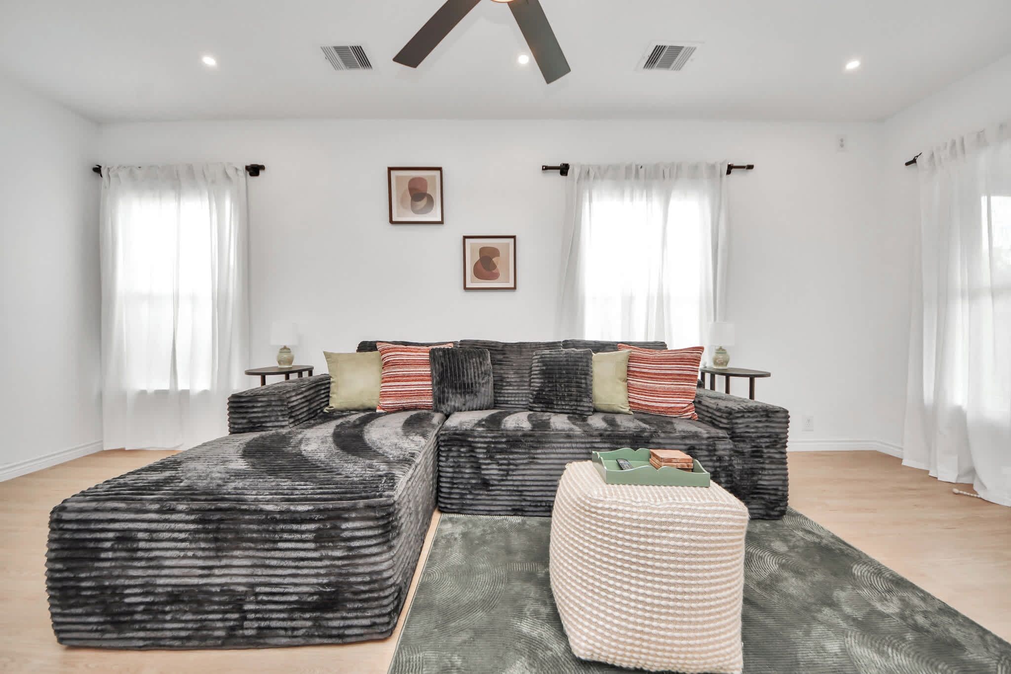 A modern living room with a sectional sofa, ottoman, and a rug.