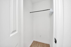 Un couloir étroit aux murs blancs et au plancher en bois.