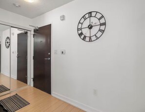 A room with a large wall clock, a door, and a mirror. - Cozy Place Steps to CN Tower & Rogers Center (Toronto)