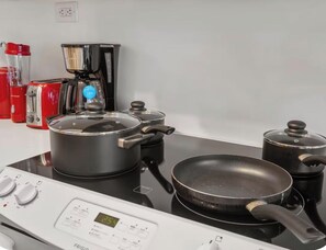 A kitchen with a stove, pots, a frying pan, and a coffee maker. - Cozy Place Steps to CN Tower & Rogers Center (Toronto)