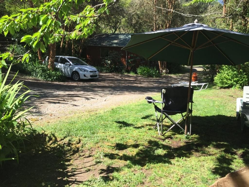 Un coche aparcado en una zona de césped con una tienda de campaña y una silla.