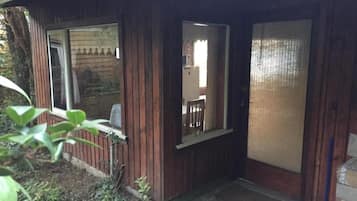 Una cabaña de madera con ventana, puerta y un pequeño porche.