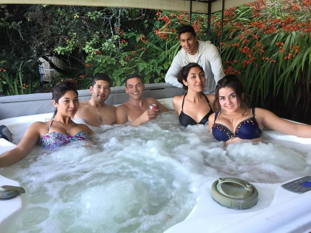 A group of people in a hot tub with a control panel and a remote control.