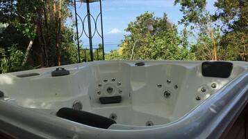 A hot tub with a view of trees and the ocean.
