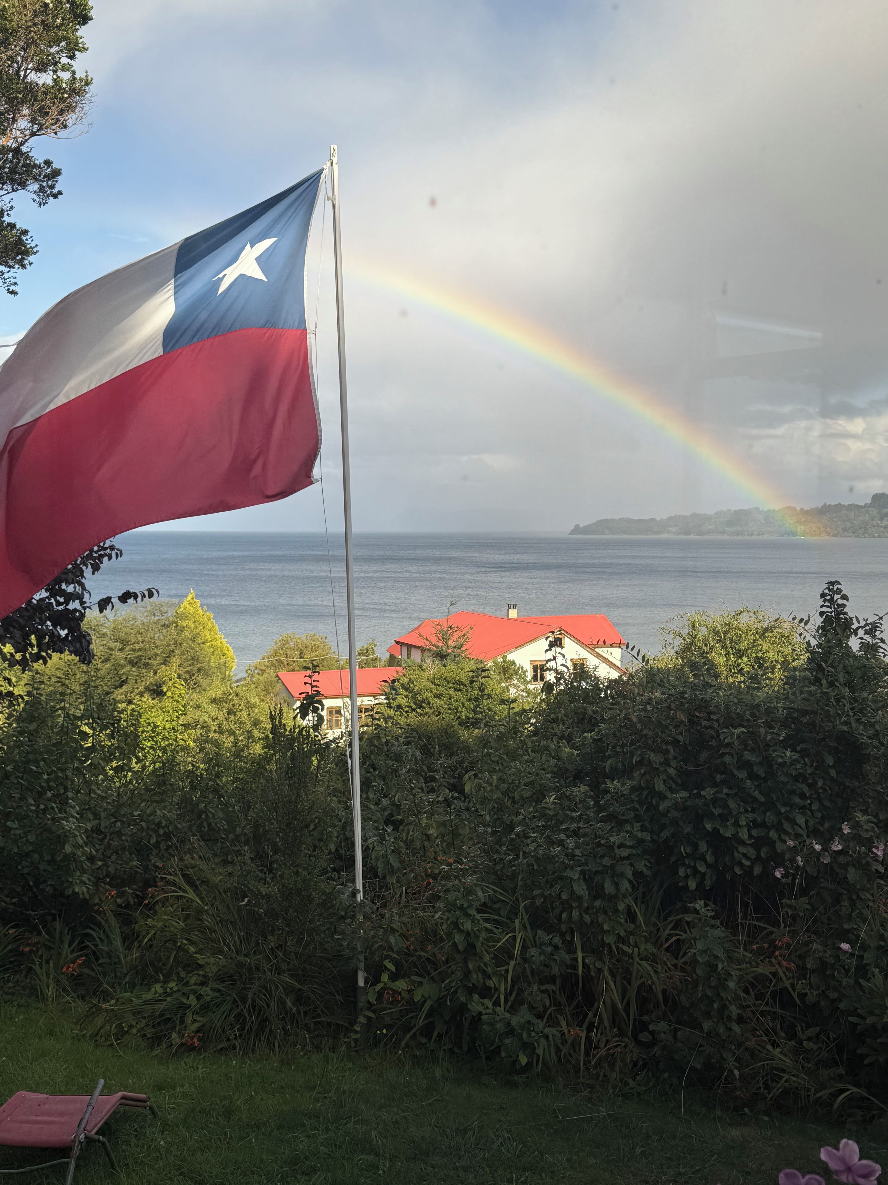 Mastro com uma bandeira, arco-íris e paisagem costeira com edifícios.