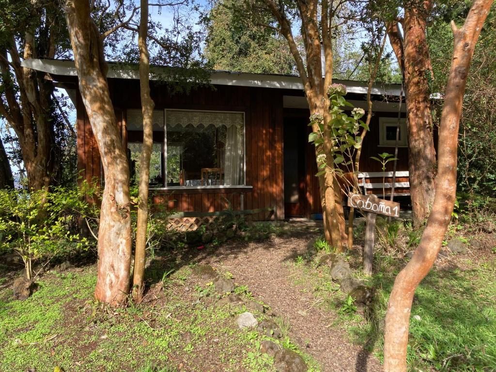 Une cabane rustique avec une façade en bois, une fenêtre ornée d’un cadre décoratif et un panneau indicateur portant un nom.