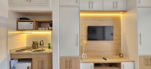 Una cocina moderna con microondas integrado, cafetera y televisor de pantalla plana montado en la pared.