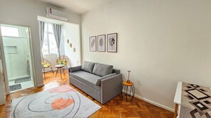 Una sala de estar con un sofá gris, una mesita redonda y un tapiz estampado.