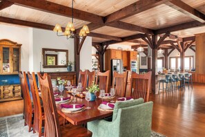 Un vaste espace dédié à la salle à manger, avec une table en bois dressée pour le repas, entourée de chaises en bois et surmontée d’un lustre.