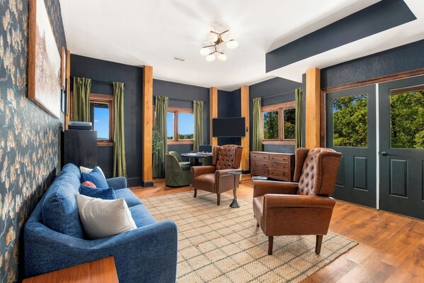 A modern living room with a blue sofa, leather armchairs, and a dining area.
