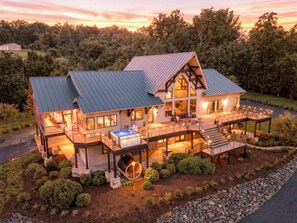 A large, multi-story house with a covered patio, a hot tub, and a well-maintained garden.