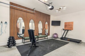 A gym with exercise equipment, mirrors, a treadmill, and a wall-mounted TV. - Shenandoah Luxury: Views and Privacy w/ Hot Tub, Sauna, Theater (Stanardsville)