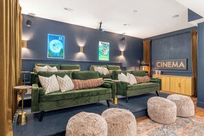 A cozy cinema room with green velvet sofas, a wooden cabinet, and a cinema-themed wall decoration. - Shenandoah Luxury: Views and Privacy w/ Hot Tub, Sauna, Theater (Stanardsville)