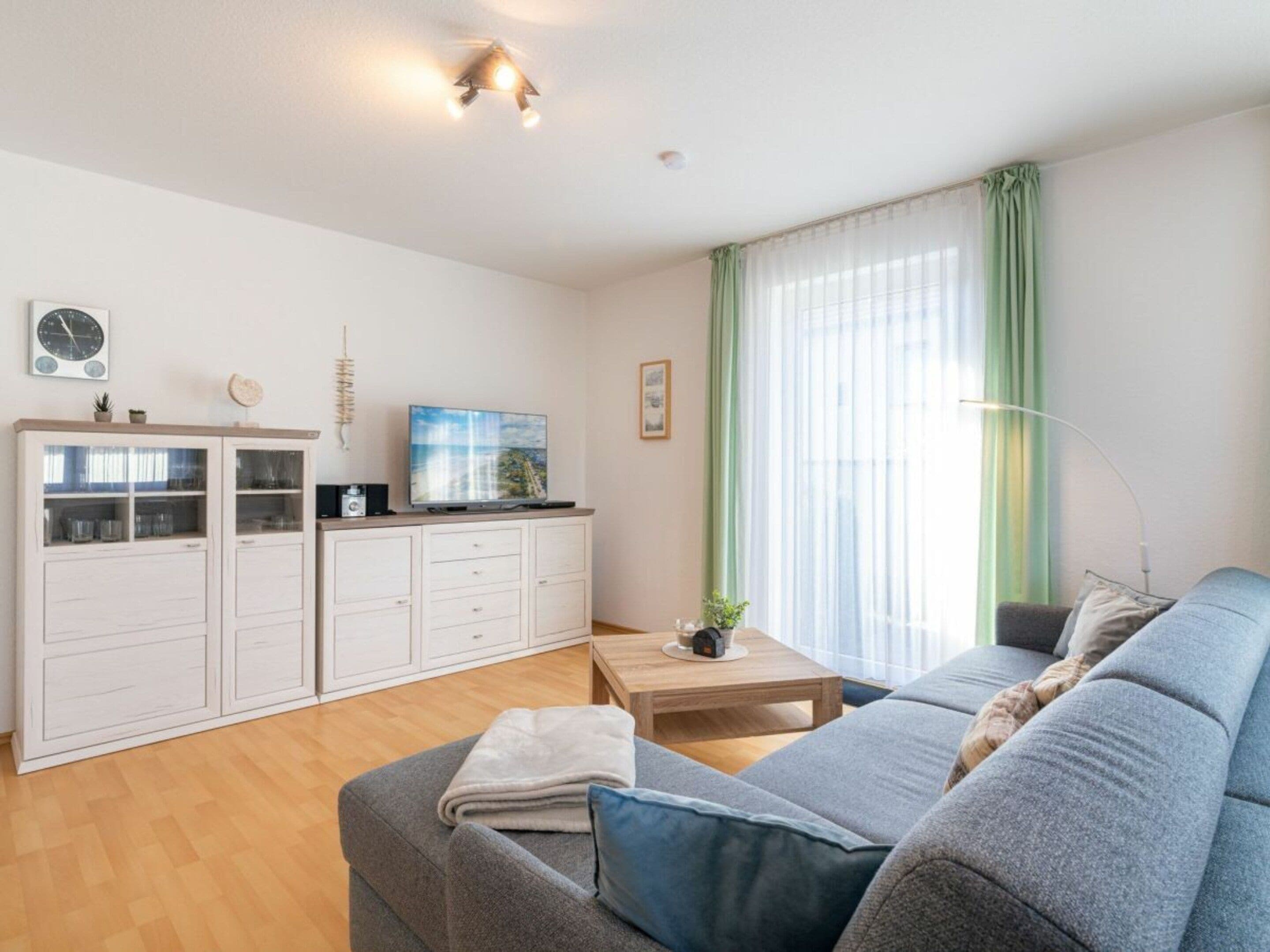 A modern living room with a sofa, a coffee table, and a TV on a cabinet.