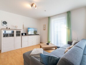 A modern living room with a sofa, a coffee table, and a TV on a cabinet. - Holiday Apartment With 1 Bedroom (Heringsdorf)