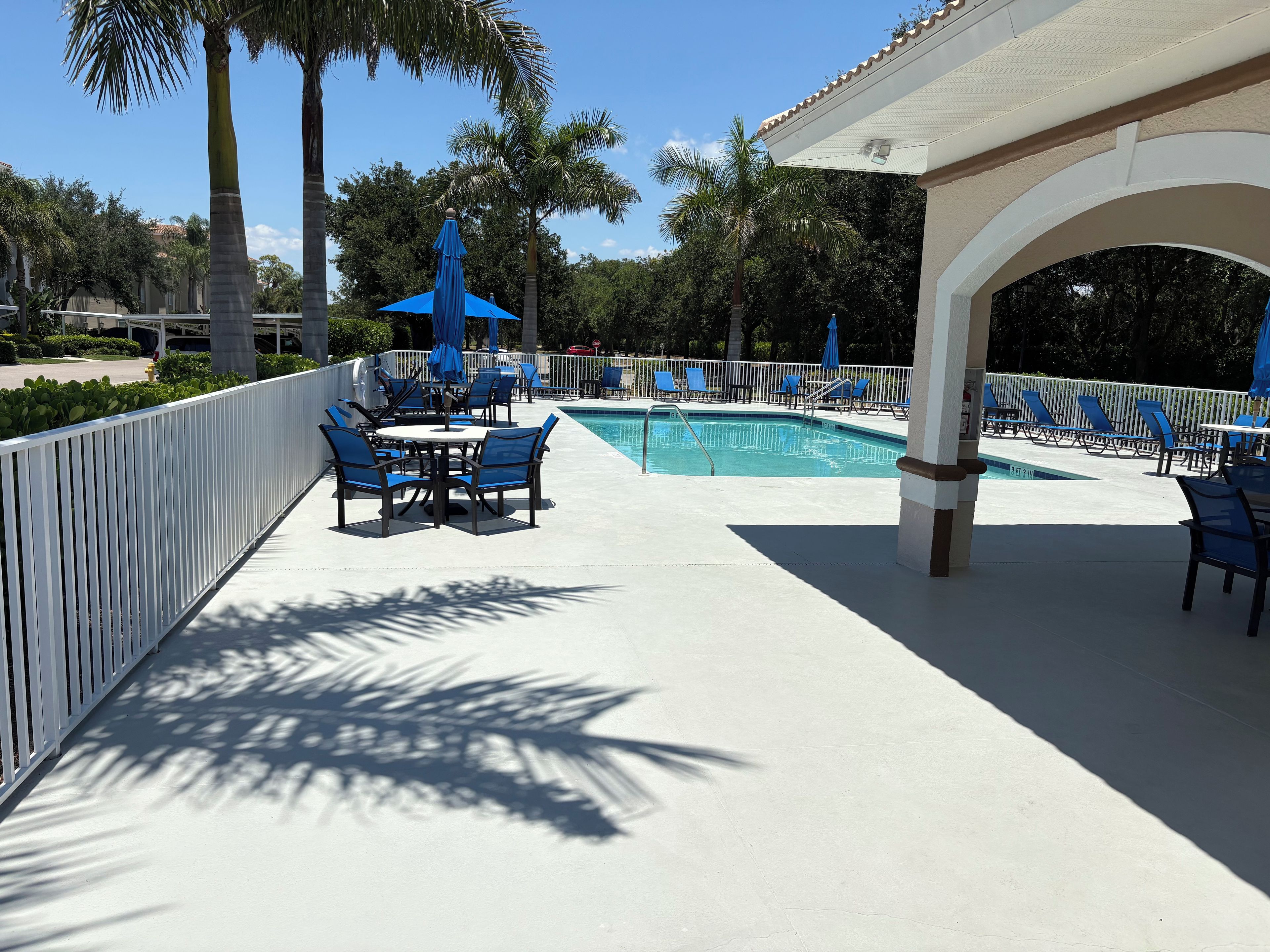 A poolside area with lounge chairs, a table, and umbrellas.