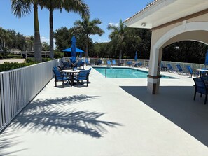 Un espace aménagé au bord de la piscine, avec des chaises longues, une table et des parasols.