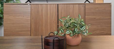 Una mesa de madera con una planta en maceta y un recipiente metálico.
