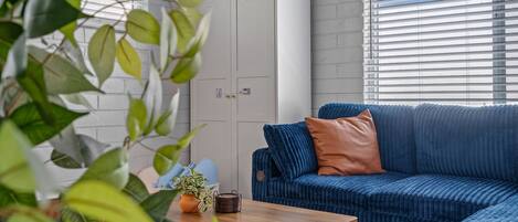 A modern living room with a blue sofa, a wooden coffee table, and a potted plant.