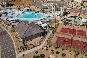 A pool area with a water slide, tennis courts, and a covered seating area.