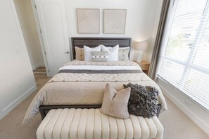 A bedroom with a bed, bedside table, lamp, and artwork on the wall.