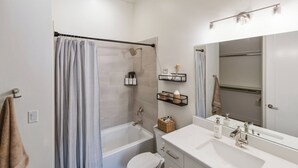 Et moderne badeværelse med badekar, toilet og vaskebord med spejl.