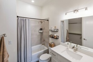 A modern bathroom with a bathtub, toilet, and vanity with a mirror.