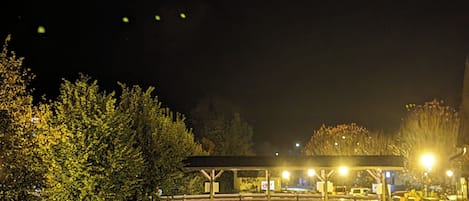 A nighttime scene with a paved pathway leading to a covered area with benches.