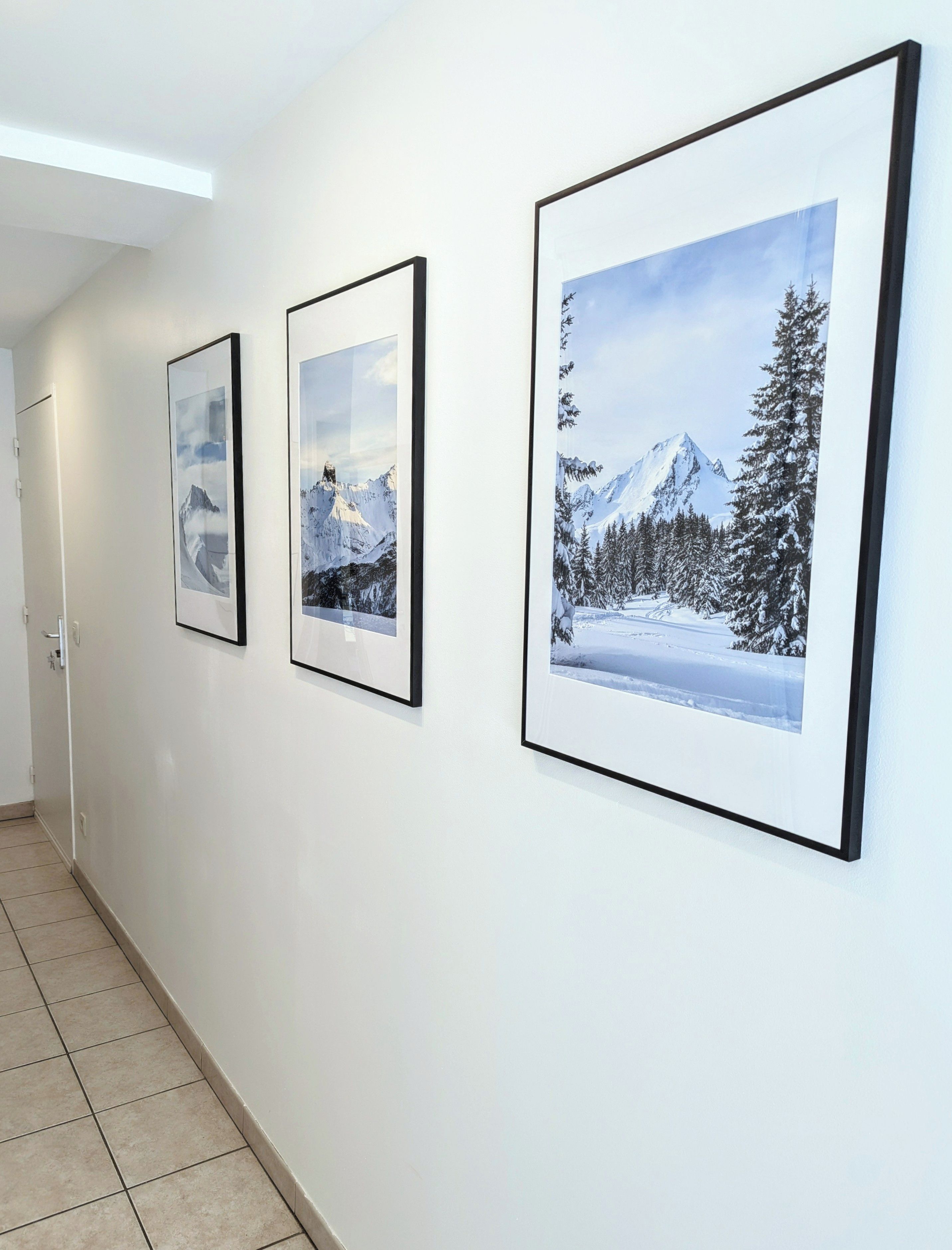 Un couloir orné de trois photographies encadrées accrochées au mur.