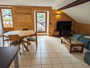 Ein gemütliches Wohnzimmer mit Holzvertäfelung, einem runden Esstisch und einem Fernseher.