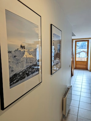 A hallway with two framed photographs of snowy mountain landscapes on the wall. - 100m² Duplex with mountain views, in the heart of Beaufort (Beaufort)