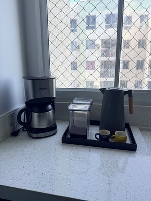 A kitchen counter with a coffee maker, a toaster, and a coffee pot. - Modern Apartment with Ocean View, Praia do Futuro | Air Conditioning and Parking Space. (Fortaleza)