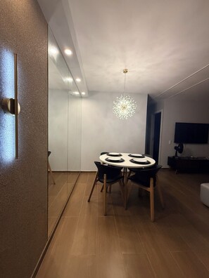 Un espace de salle à manger moderne, avec une table ronde, des chaises et un luminaire au plafond au design original.