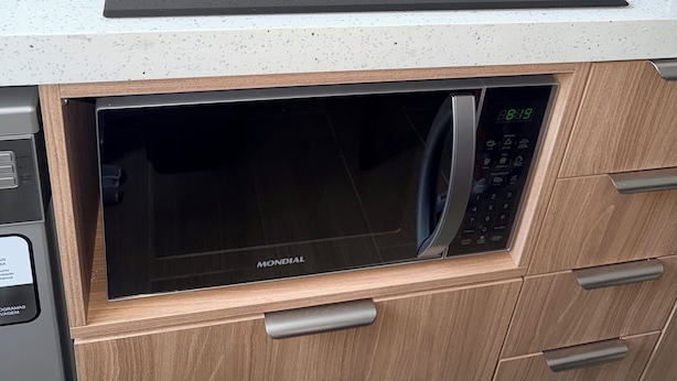 A kitchen with a built-in microwave and a black induction cooktop. - Modern Apartment with Ocean View, Praia do Futuro | Air Conditioning and Parking Space. (Fortaleza)