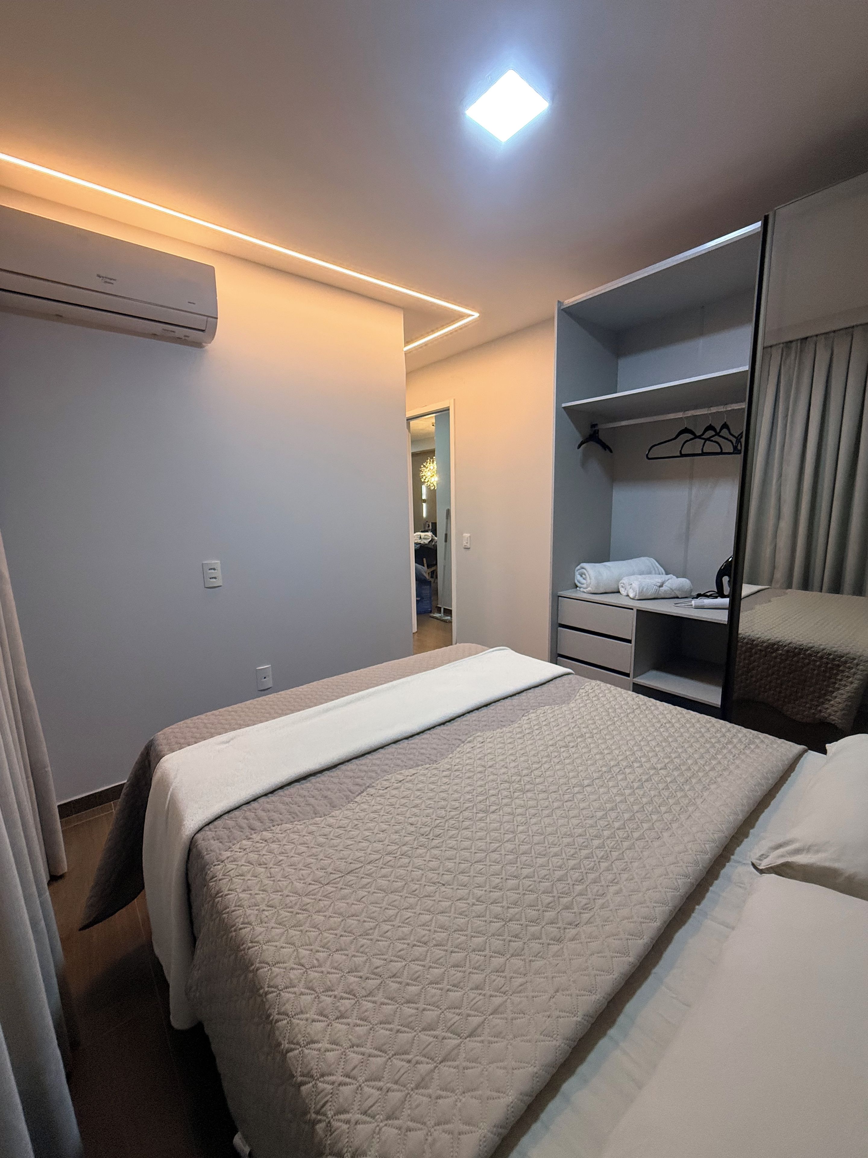 Ein Hotelzimmer mit Bett, Kleiderschrank, Spiegel und Deckenleuchte.