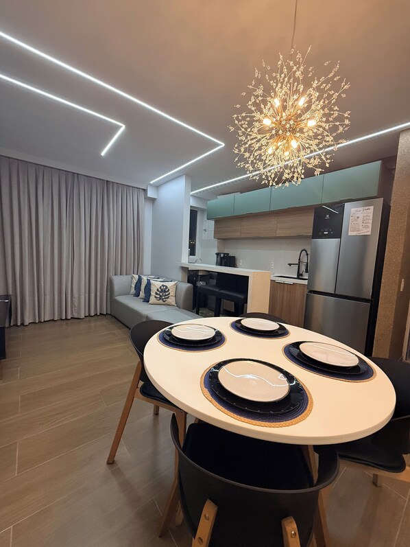 Une cuisine moderne dotée d’un réfrigérateur encastré, d’une table à manger avec de l’assiette et d’un luminaire suspendu.