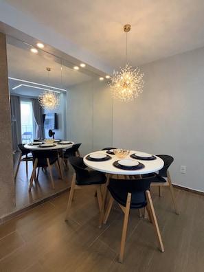A modern dining area with a round table, black chairs, and a unique chandelier. - Modern Apartment with Ocean View, Praia do Futuro | Air Conditioning and Parking Space. (Fortaleza)