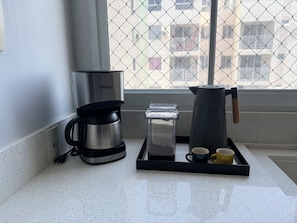 Eine Küchenzeile mit einer Kaffeemaschine, einem Wasserspender und einem Kaffeekocher auf einer Arbeitsfläche.