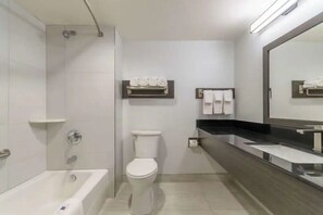 Ein modernes Badezimmer mit Badewanne, Toilette und einem großen Spiegel.