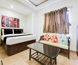 A hotel room with a bed, a sofa with patterned cushions, a coffee table, and a window with curtains. - Saver Double Hotel Grey Jade (Vasco da Gama)