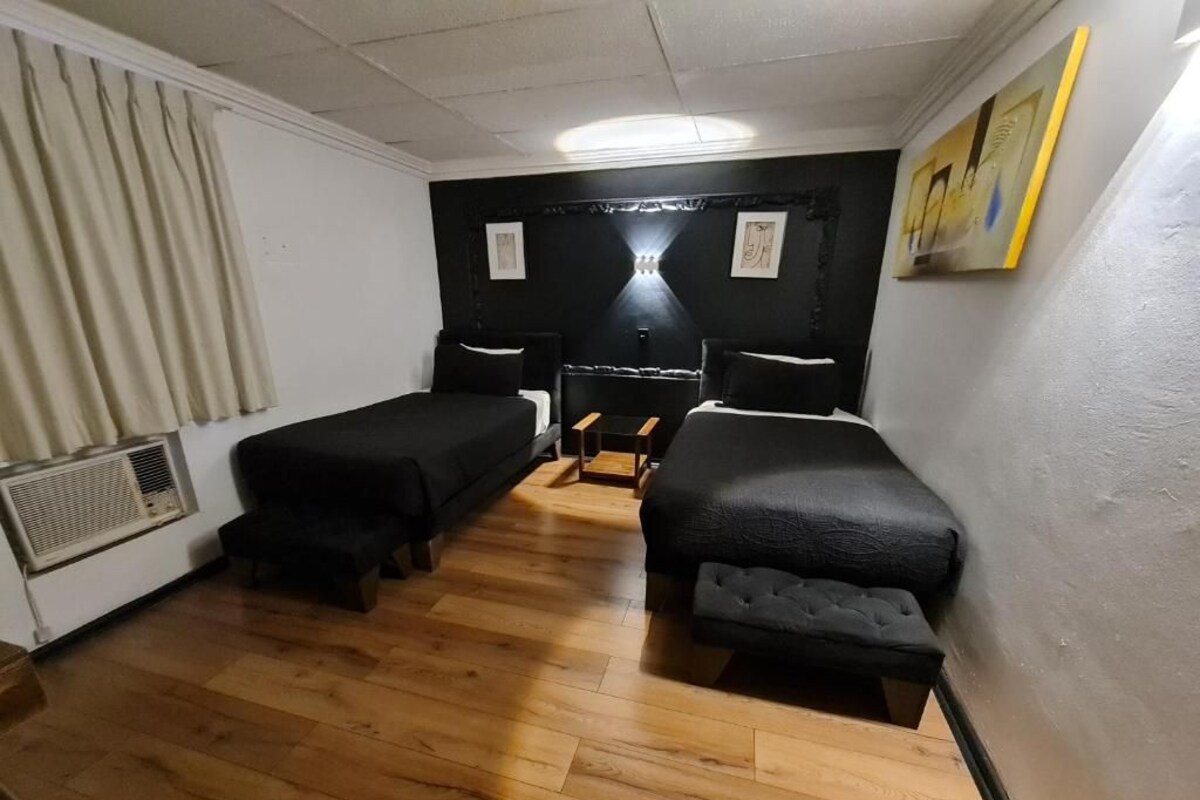 A room with two beds, a small table, and a radiator.