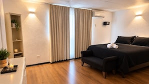 A hotel room with a bed, a sofa, a small table with a plant, and a wall-mounted air conditioner. - LRH Santiago (Santiago)