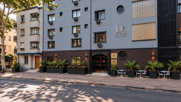 A hotel with a modern facade, outdoor seating, and a visible entrance. - LRH Santiago (Santiago)