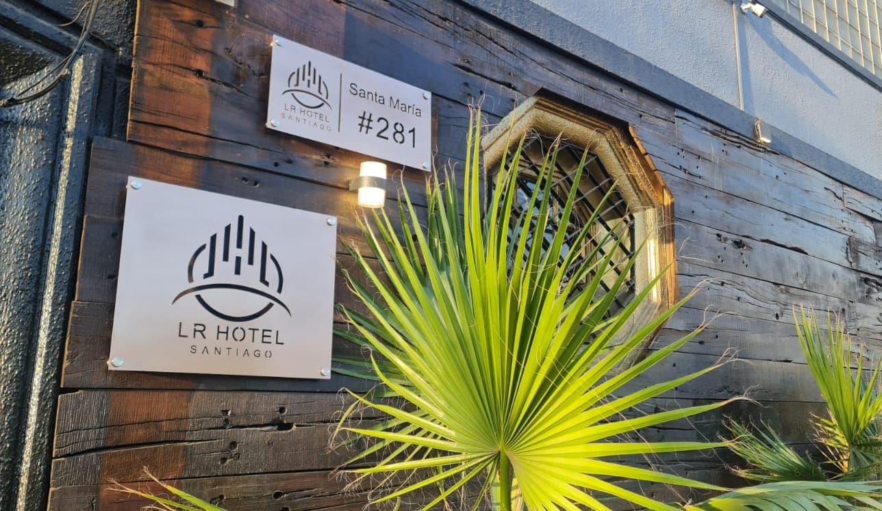 Un edificio de madera con letreros que indican 'Santa Maria #281' y 'LR Hotel Santiago'.