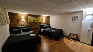 A room with two beds, wooden flooring, a wall-mounted light fixture, and a framed picture. - LRH Santiago (Santiago)