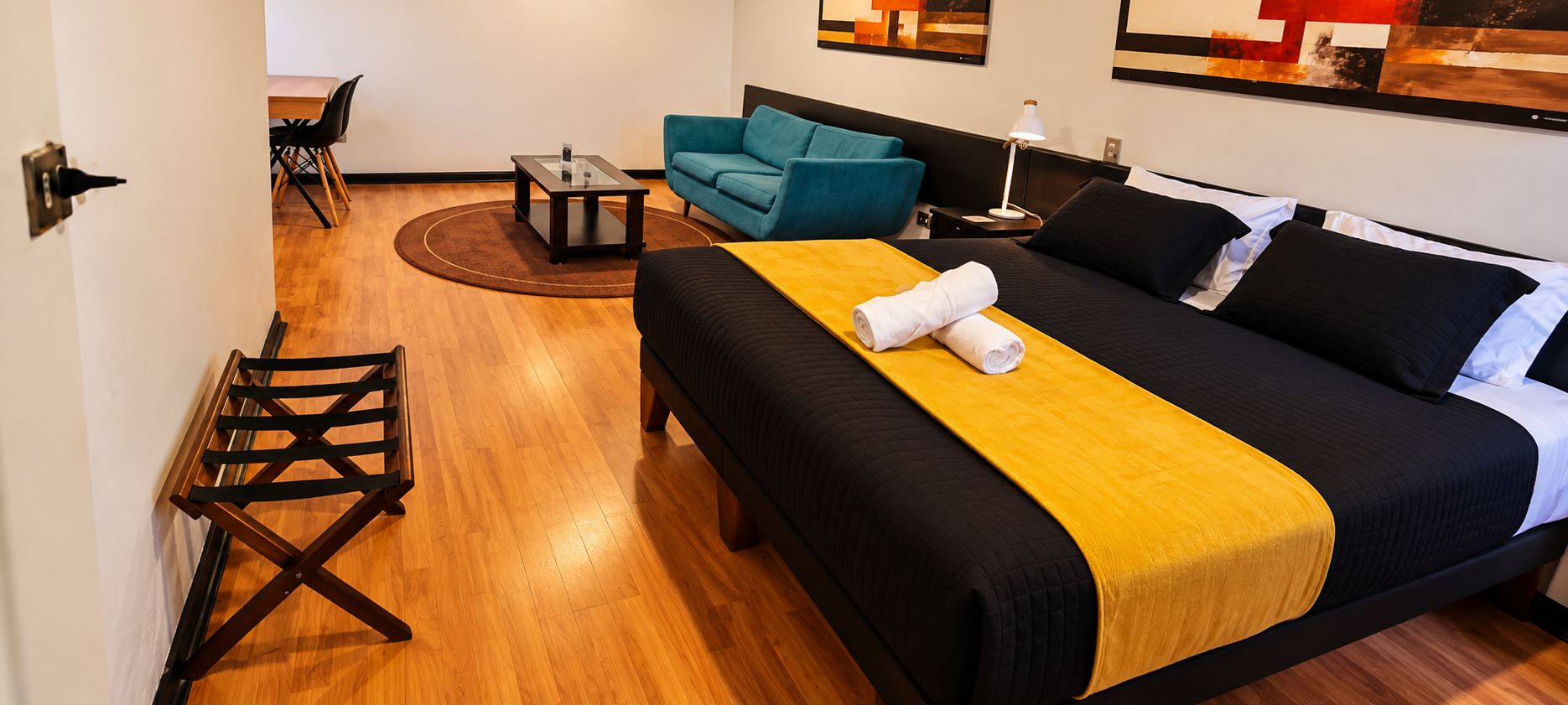 Una habitación de hotel con cama, sofá, una mesita y una silla.
